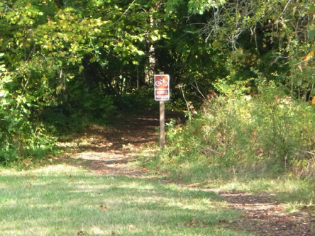 Natural surface trail goes through the woods – sign says bikes prohibited